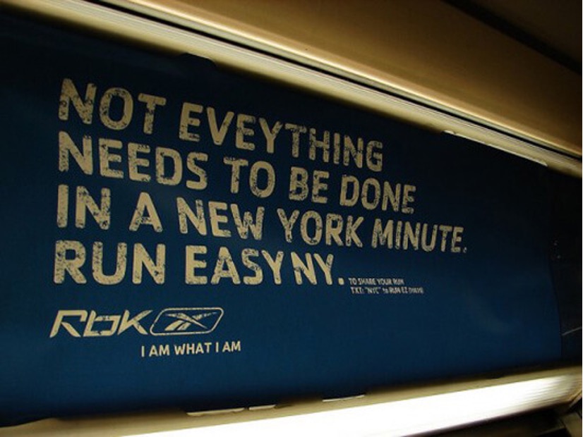 A poster on the tube that says. Not eveything needs to be done in a new york minute. Run Easy NY, in white writing on a dark blue background.